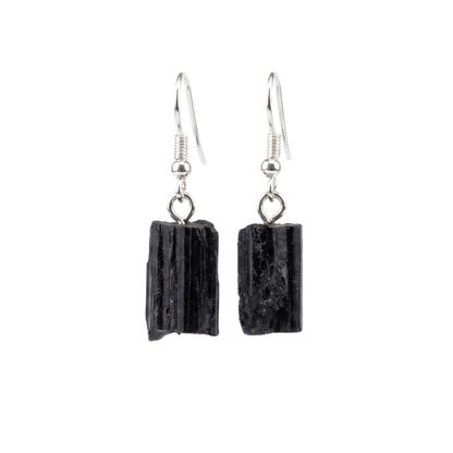 Pair of natural raw black tourmaline dangle earrings with gold-plated classic fishhook wires on a seamless white background. Protection jewelry.