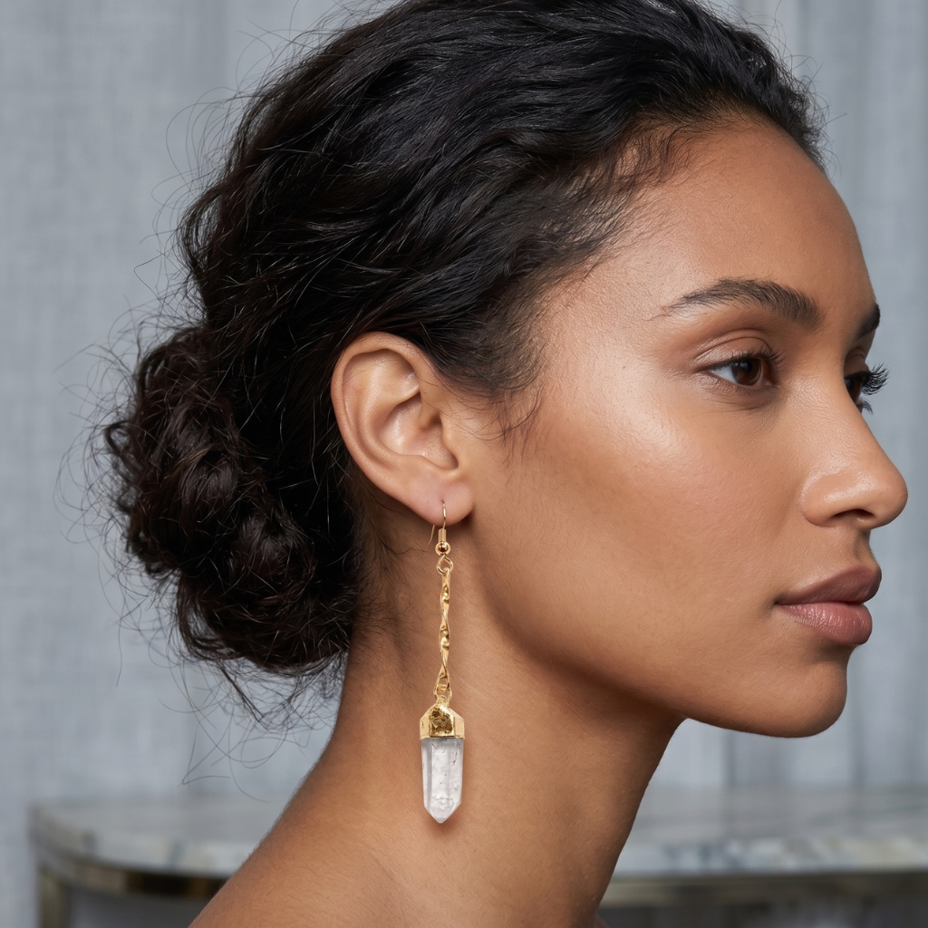 Close-up profile of a female model wearing a premium plated long raw Clear Quartz point drop earring. High-vibe wellness fashion jewelry.
